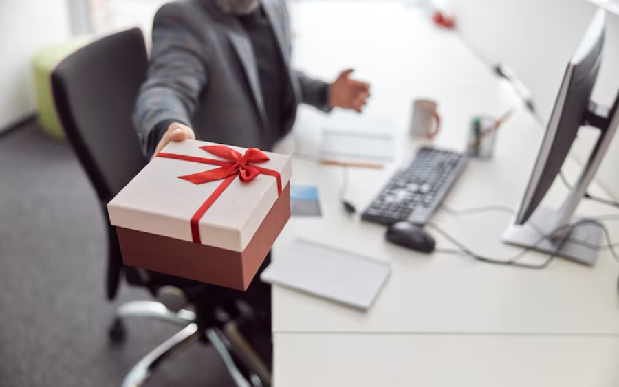 Idées cadeaux d'entreprise au travail : un manager remet à un salarié un cadeau emballé au bureau